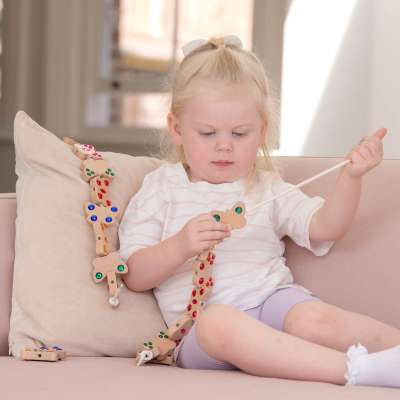 Et barn sidder i en sofa og leger med tickit® Sommerfugleperler i træ