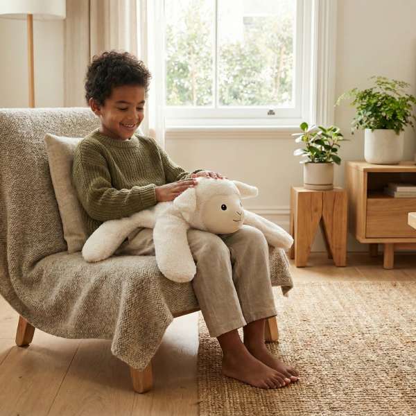 En dreng sidder i en stol sammen med Lam bamsepude med tyngde