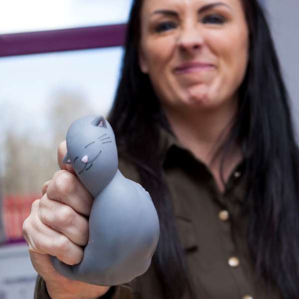 En kvinde giver Karma Kitty fidget – antistress klemmedyr et klem med den ene hånd