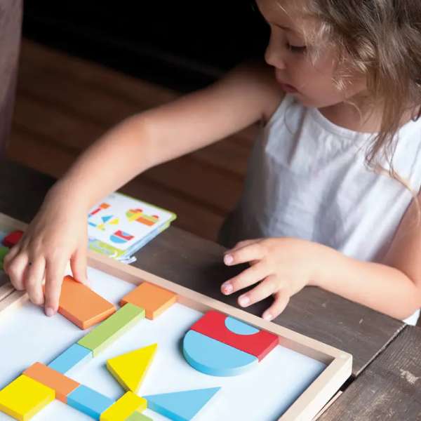 Pige er igen med at lege Magnetiske former i træ – læringsspil der udvikler farve- og formgenkendelse.