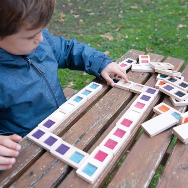 Et barn side ud i en have og leje med Andreu Toys taktil domino – 