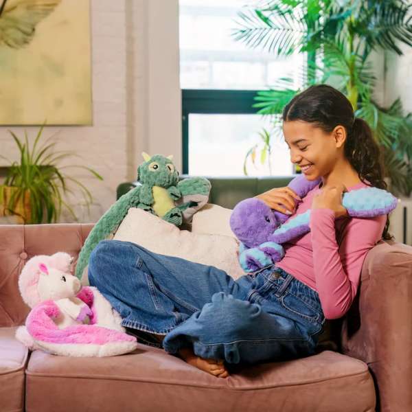 Barn sidder med Blæksprutten Indigo Hugaround i sofa – ideel til ro, hygge og sansestimulering

