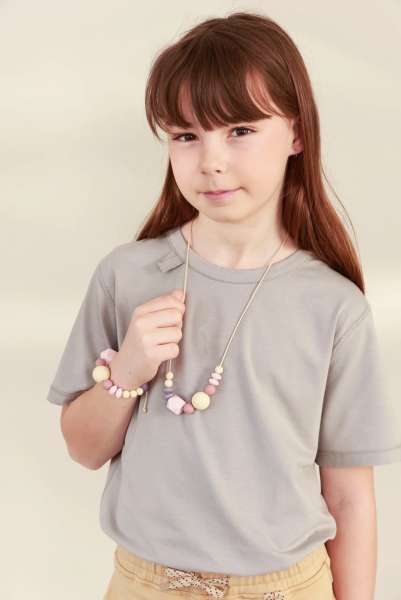Barn med CalmBeads halskæde og matchende armbånd med sensoriske perler i rolige pastelfarver.
