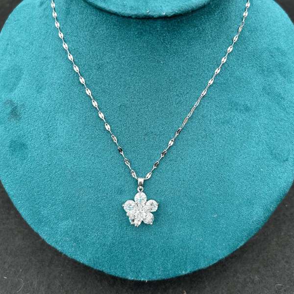 Geranium fidgethalskæde båret som elegant smykke med blomstervedhæng – diskret fidgethalskæde til unge og voksne med behov for sensorisk stimulering.

