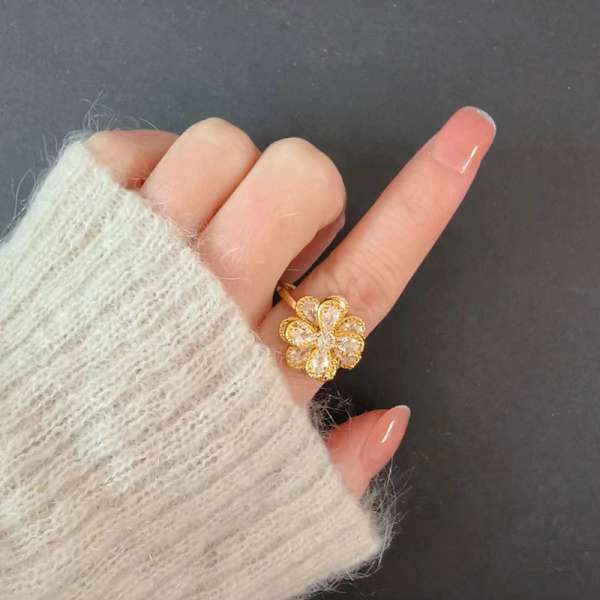Camellia fidgetring båret på fingeren – guldfarvet fidgetsmykke med blomsterdesign til koncentration, ro og uro i hænderne.
