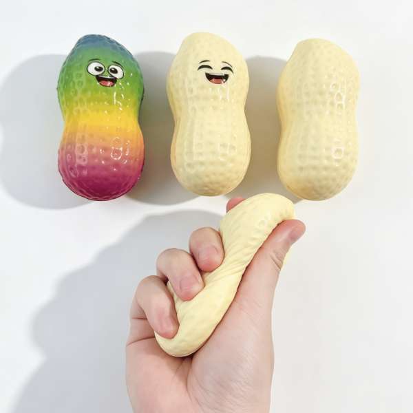 Squishy Peanut klemt i hånden, der viser den bløde slow-rise effekt – sensorisk fidget til stressreduktion, fokus og sansestimulering.